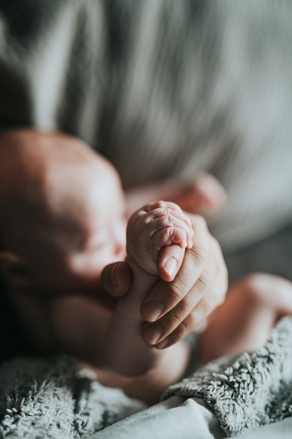 Tiny newborn hand held by a parent